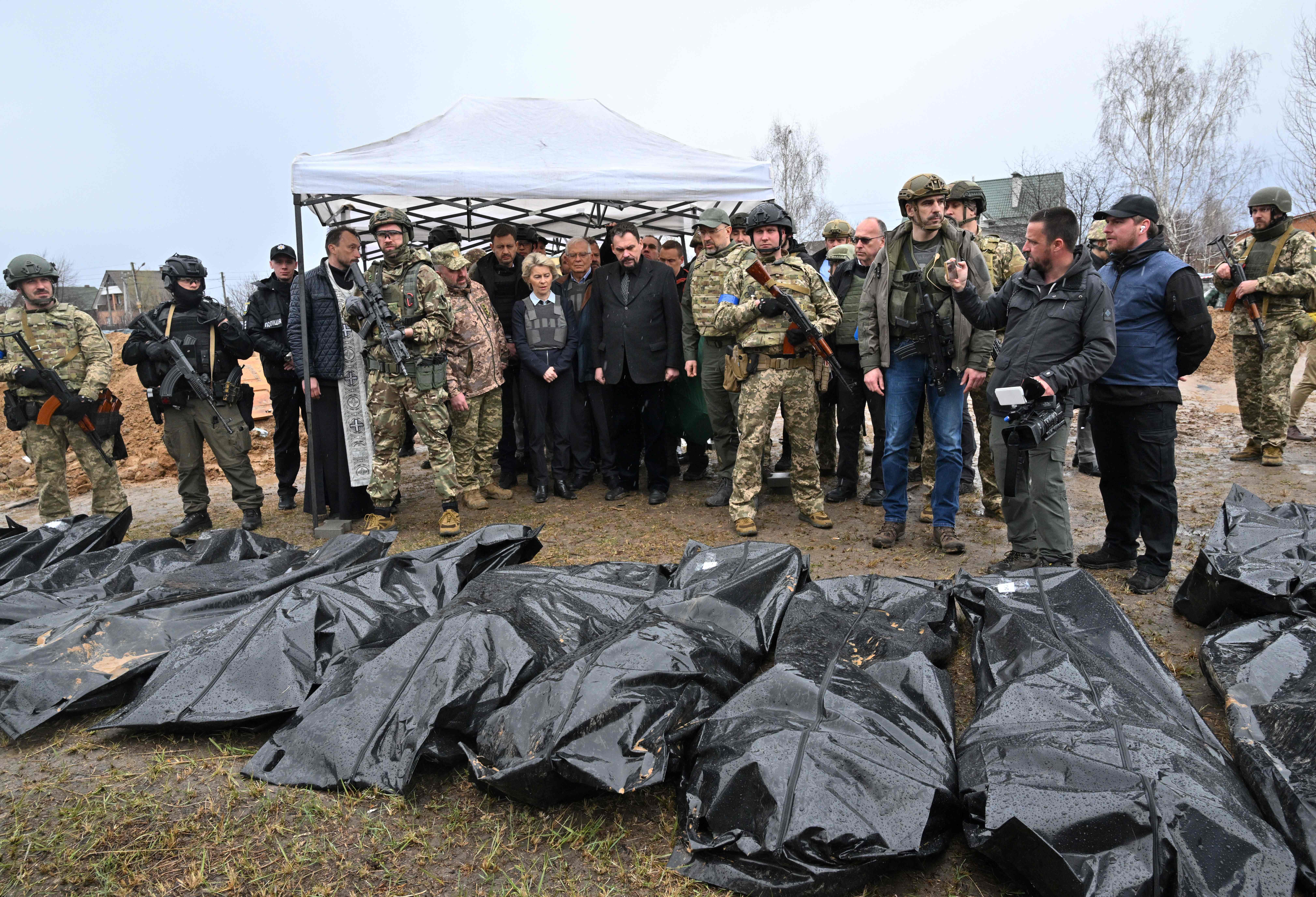 European Commission President Ursula von der Leyen, is flanked by Slovakia's Prime Minister Eduard Heger and European Union High Representative for Foreign Affairs and Security Policy Josep Borrell as they visit a mass grave in the town of Bucha, northwest of Kyiv on April 8, 2022. - European Commission President Ursula von der Leyen on April 8, 2022, visited a mass grave in Bucha, a town outside Kyiv where Russian forces are accused by Ukraine's allies of carrying out atrocities against civilians. An AFP journalist reported that von der Leyen was in the town north of the capital as part of a trip to shore up support for Ukraine alongside the bloc's foreign policy chief Josep Borrell.