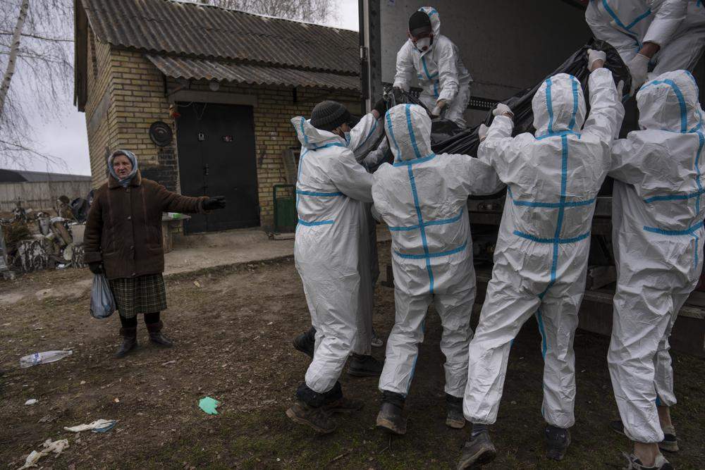 Nadiya Trubchaninova, 70, left, stands next to volunteers while loading a plastic bag that contains the body of a civilian killed by Russian soldiers into a truck, in Bucha, on the outskirts of Kyiv, Ukraine, Tuesday, April 12, 2022.
