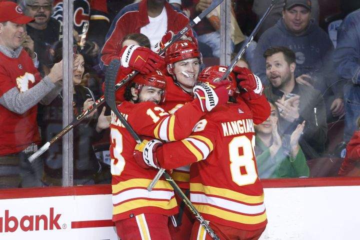 Calgary Flames left wing Matthew Tkachuk (19) celebrates his 40th goal and his 100th point of the season with teammates Johnny Gaudreau (13) and Andrew Mangiapane (88) during second period NHL hockey action against the Dallas Stars in Calgary on Thursday April 21, 2022.