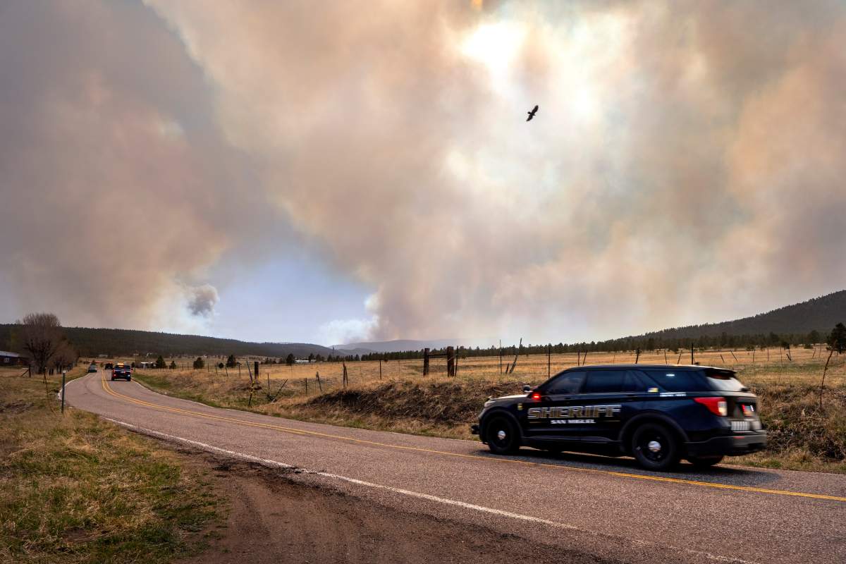 San Miguel County Sheriff’s Officers patrol N.M. 94 near Penasco Blanco, N.M., as the Calf Fire burns nearby on Friday, April 22, 2022. Destructive Southwest fires have burned dozens of homes in northern Arizona and put numerous small villages in New Mexico in the path of danger, as wind-fueled flames chewed up wide swaths of tinder-dry forest and grassland and towering plumes of smoke filled the sky.