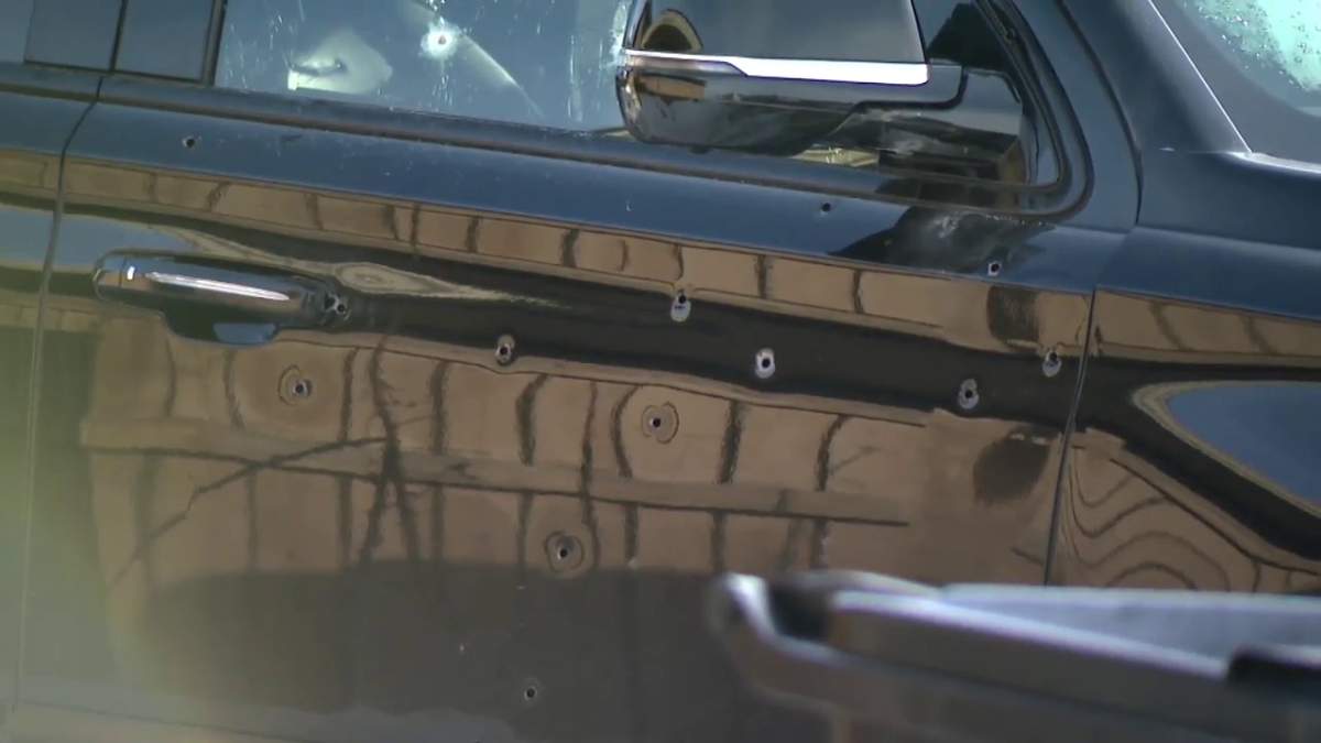 Bullet holes on the side of a black truck.