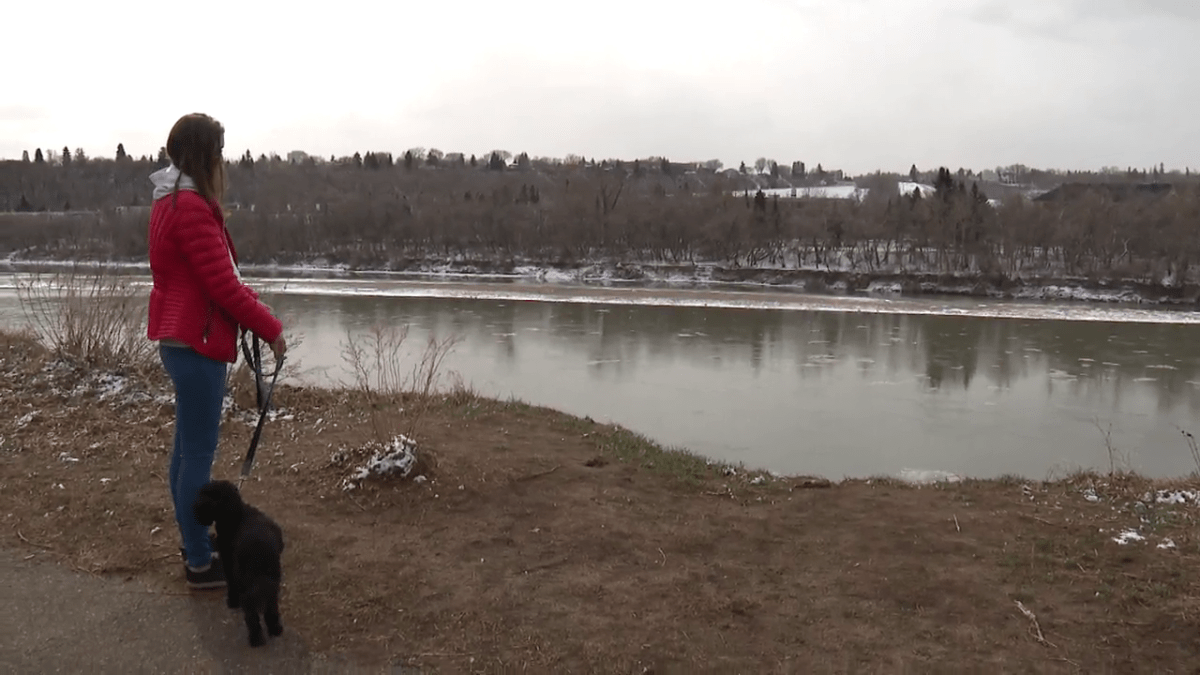 Maia Stock stands with her dog Brady near where she fell down the river embankment on April 13, 2022.