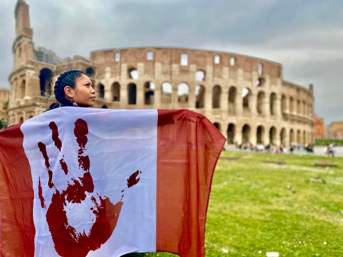 Palexelsiya Lorelei Williams drapes the genocide flag of Canada over her shoulders in front of the Colosseum in Rome on Mon. March 28, 2022.