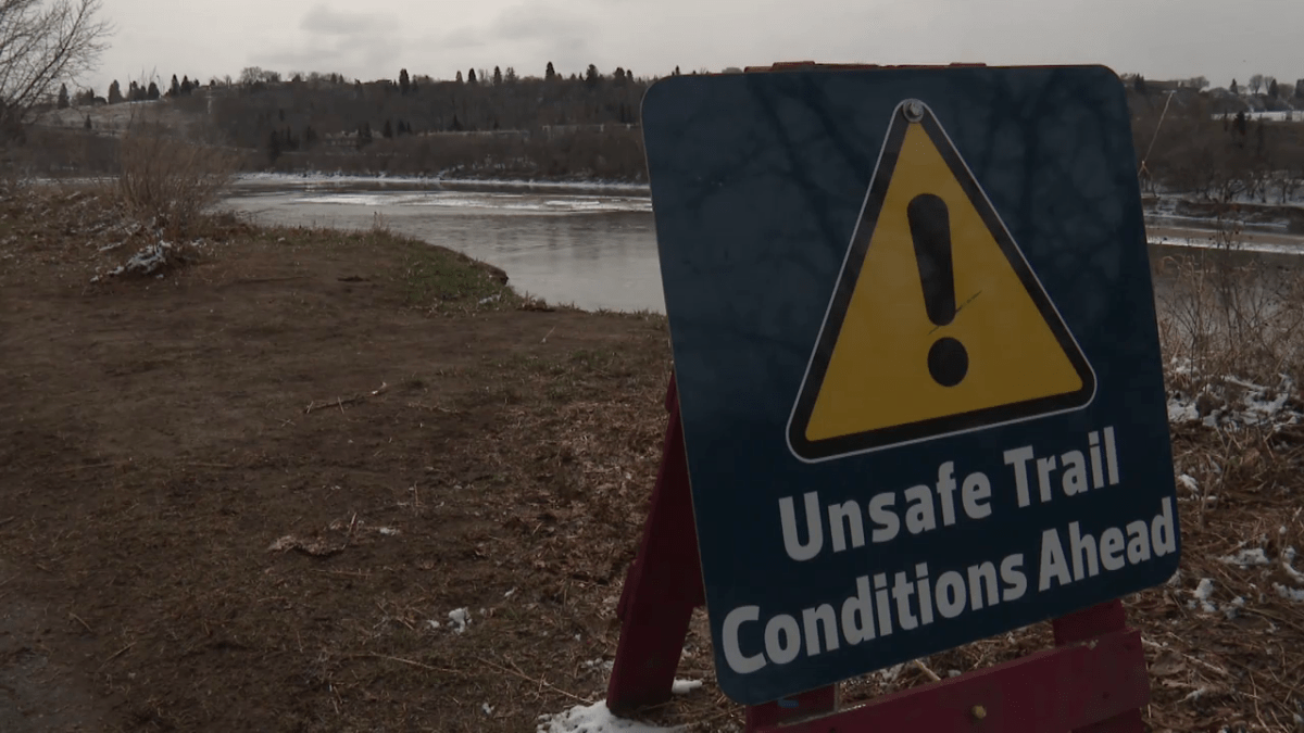 Unsafe trail condition signs now sit along a path in Riverdale after an Edmonton woman fell down the embankment on April 13, 2022.