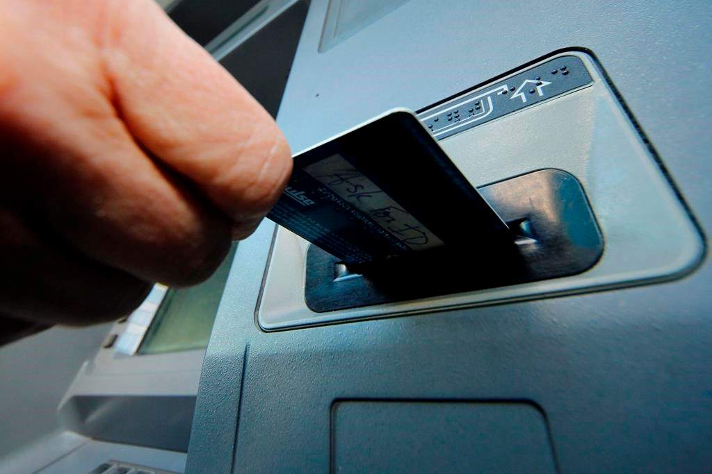 A person inserts a debit card into an ATM.