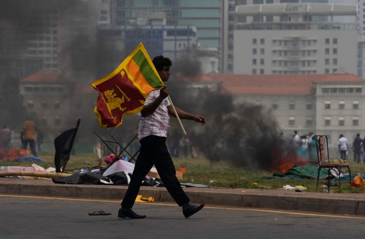 A Sri Lankan government supporter carries a national flag after attacking the anti government protest site outside president’s office in Colombo, Sri Lanka, Monday, May 9, 2022.