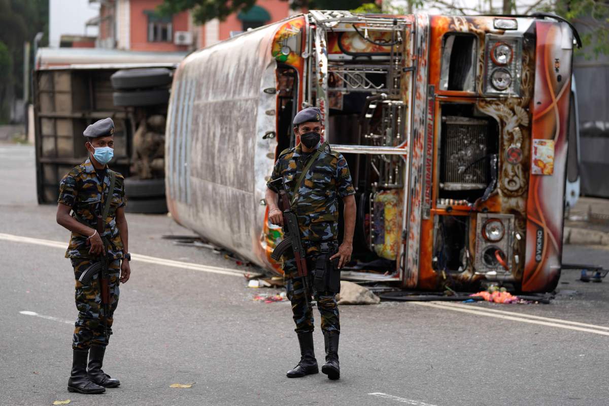 Sri Lankan soldiers stand guard next to burnt buses a day after clashes between government supporters and anti-government protesters in Colombo, Sri Lanka, Tuesday, May 10, 2022.