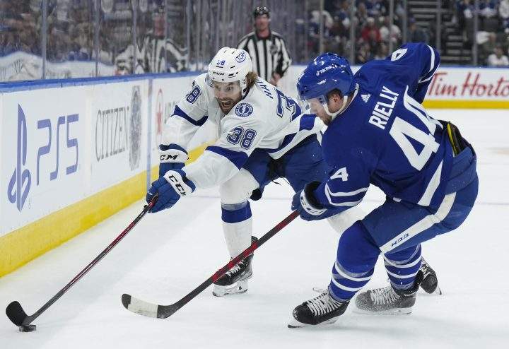 Toronto Maple Leafs defenceman Morgan Rielly (44) battles for the loose puck against Tampa Bay Lightning forward Brandon Hagel (38) during first period, round one, NHL Stanley Cup playoff hockey action in Toronto on Tuesday, May 10, 2022.