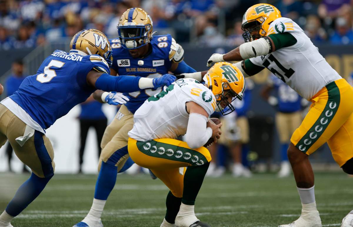 Edmonton Elks quarterback Nick Arbuckle (9) scrambles away from Winnipeg Blue Bombers' Willie Jefferson (5) during the first half of pre-season CFL action in Winnipeg, Friday, May 27, 2022.