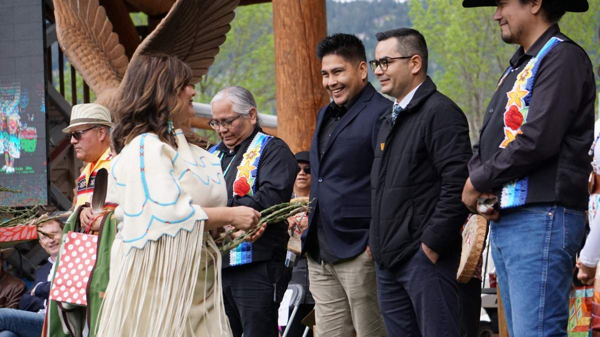 Kúkpi7 Rosanne Casimir hands braided sweetgrass to members of the culture and language team at Tk’emlúps te Secwépemc during the one-year memorial for Le Estcwicwéy̓ in Kamloops, B.C. on May 23, 2022.