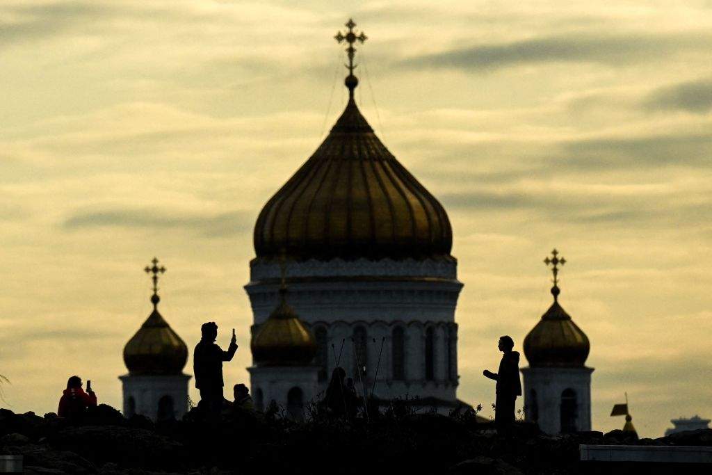 A couple rest in Zaryadye park with the Christ the Savior Cathedral on the background during the sunset in downtown Moscow on April 19, 2022.