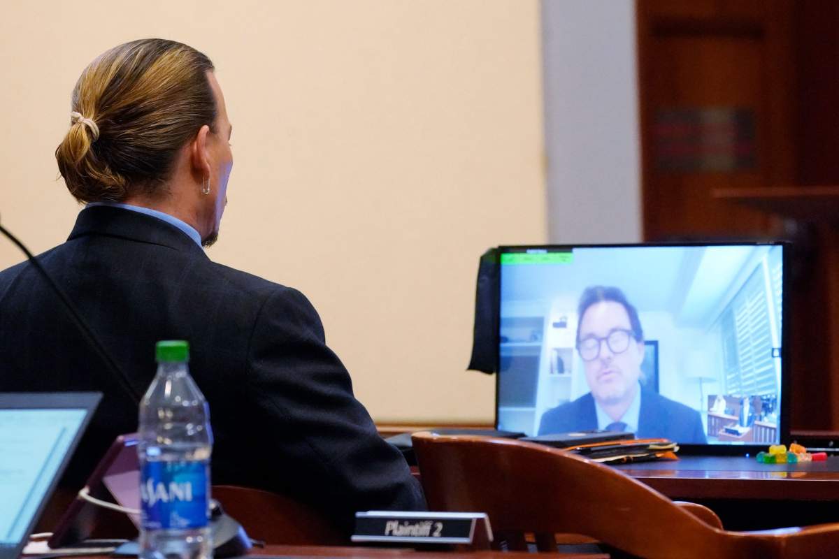 US actor Johnny Depp listens as Jack Whigham, talent manager for Depp, is seen on a monitor as he testifies remotely in the courtroom at the Fairfax County Circuit Court in Fairfax, Virginia, on May 2, 2022.