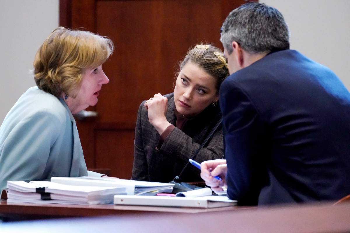 Actor Amber Heard talks to her attorneys in the courtroom at the Fairfax County Circuit Court in Fairfax, Virginia, on May 2, 2022.