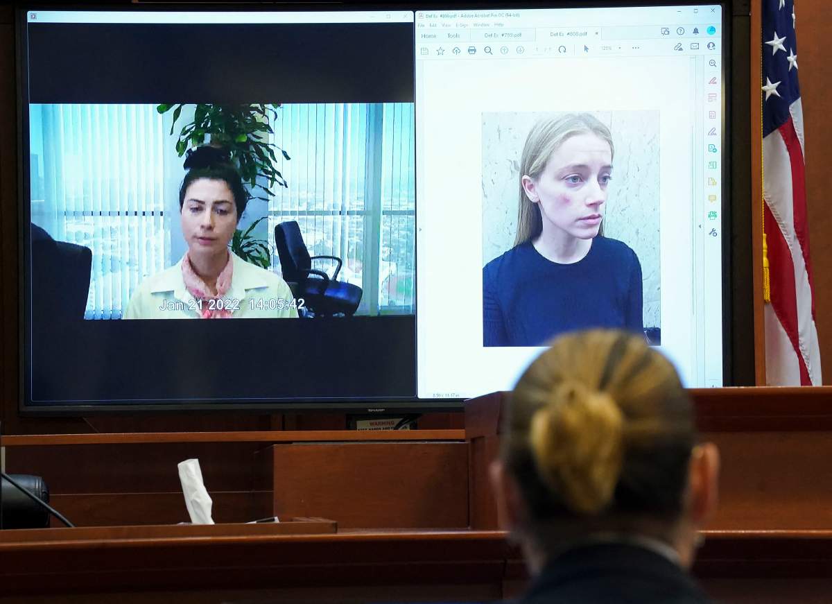 Actor Johnny Depp listens as Raquel Pennington testifies in a previously recorded video deposition, as a picture of Amber Heard is seen on screen, during his defamation trial against his ex-wife Amber Heard at the Fairfax County Circuit Courthouse in Fairfax, Virginia, on May 18, 2022.