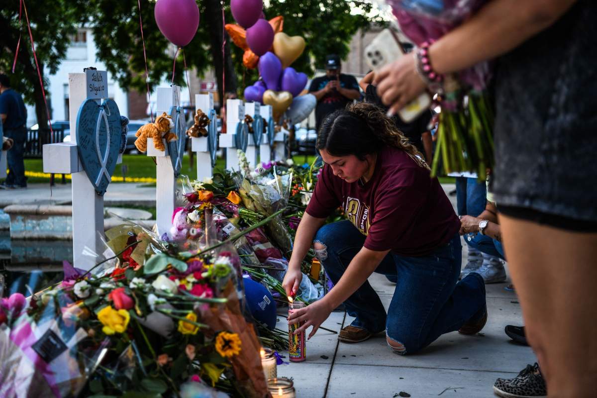 A woman lights a candle at a makeshift memorial outside Uvalde County Courthouse in Uvalde, Texas, on May 26, 2022. - Texas police faced angry questions May 26, 2022 over why it took an hour to neutralize the gunman who murdered 19 small children and two teachers in Uvalde, as video emerged of desperate parents begging officers to storm the school.