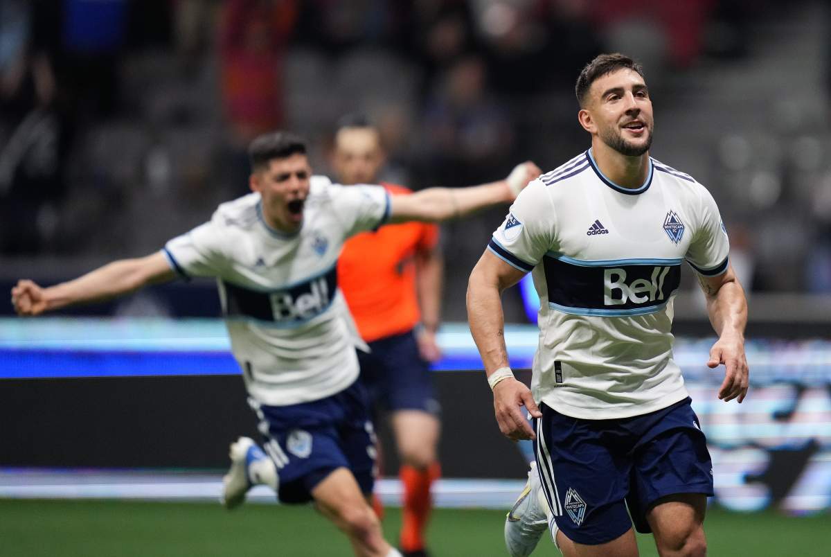 Lucas Cavallini of the Vancouver Whitecaps, right, looks on after scoring on a penalty kick during MLS action against FC Dallas in Vancouver on Wednesday while teammate Cristian Gutierrez, rear, celebrates.