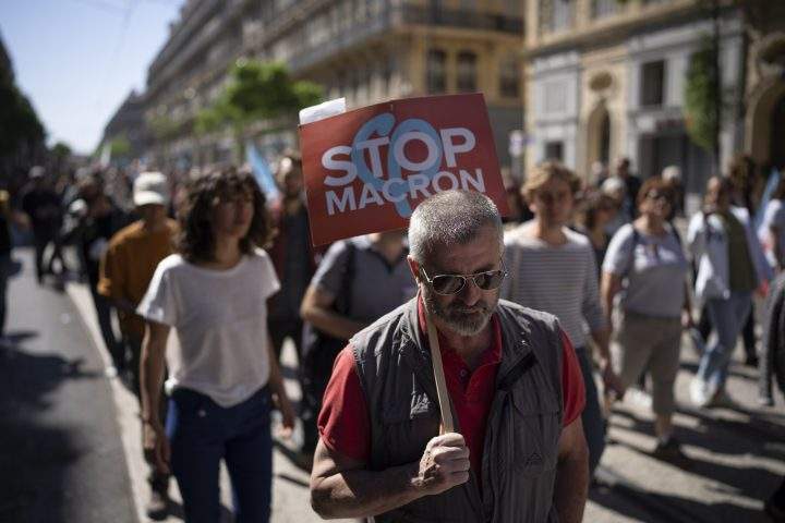A protester holds a sign reading “Stop Macron” during a May Day demonstration in Marseille, southern France, Sunday, May 1, 2022.