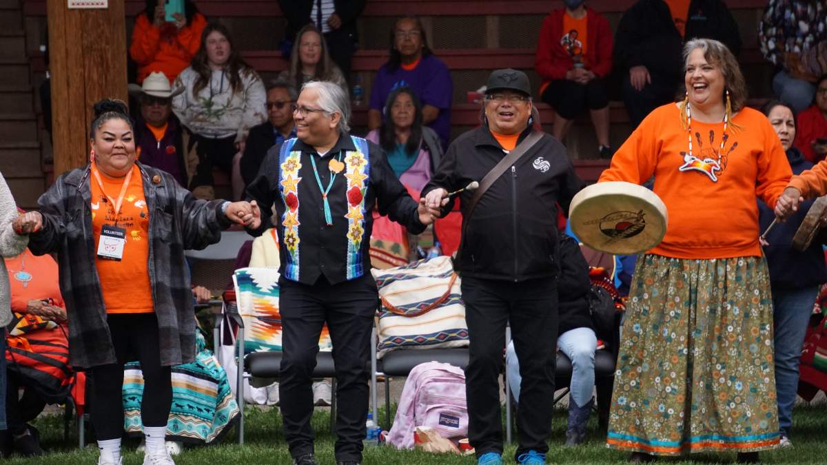 People join hands in a round dance around the Tk’emlúps te Secwépemc Powwow Arbour during the one-year memorial for the 215 missing children believed to lie in unmarked burial sites near the former Kamloops Indian Residential School, on Mon. May 23, 2022.
