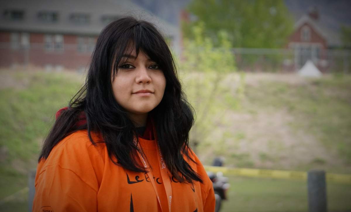 Nineteen-year-old Shelby Symes of the Ashcroft Indian Band stands in front of the Kamloops Indian Residential School during the one-year memorial for Le Estcwicwéy̓ in Kamloops, B.C. on Mon. May 23, 2022.