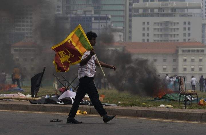 A Sri Lankan government supporter carries a national flag after attacking the anti government protest site outside president’s office in Colombo, Sri Lanka, Monday, May 9, 2022.