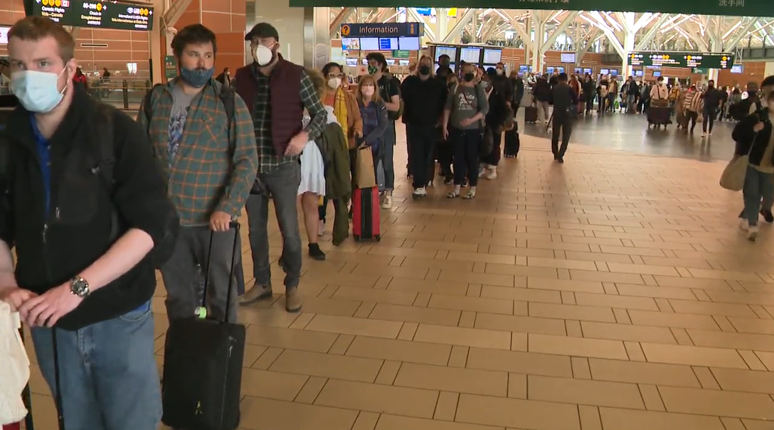 A long line of passengers is seen waiting outside the security screening area at the Vancouver International Airport on Sunday, May 1, 2022. 