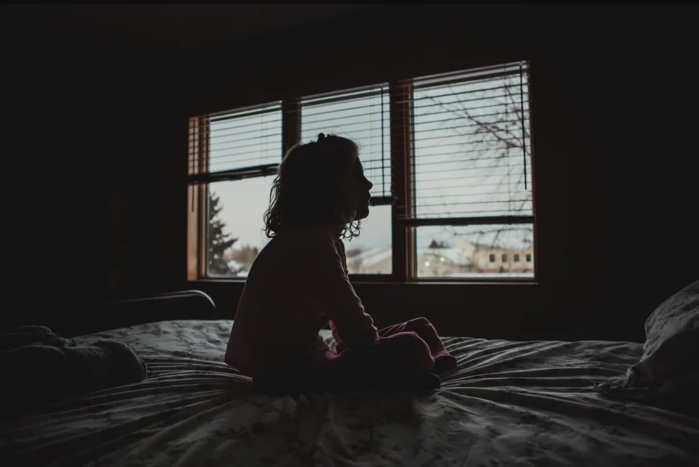 Silhouette of Little girl sitting on bed mental health children