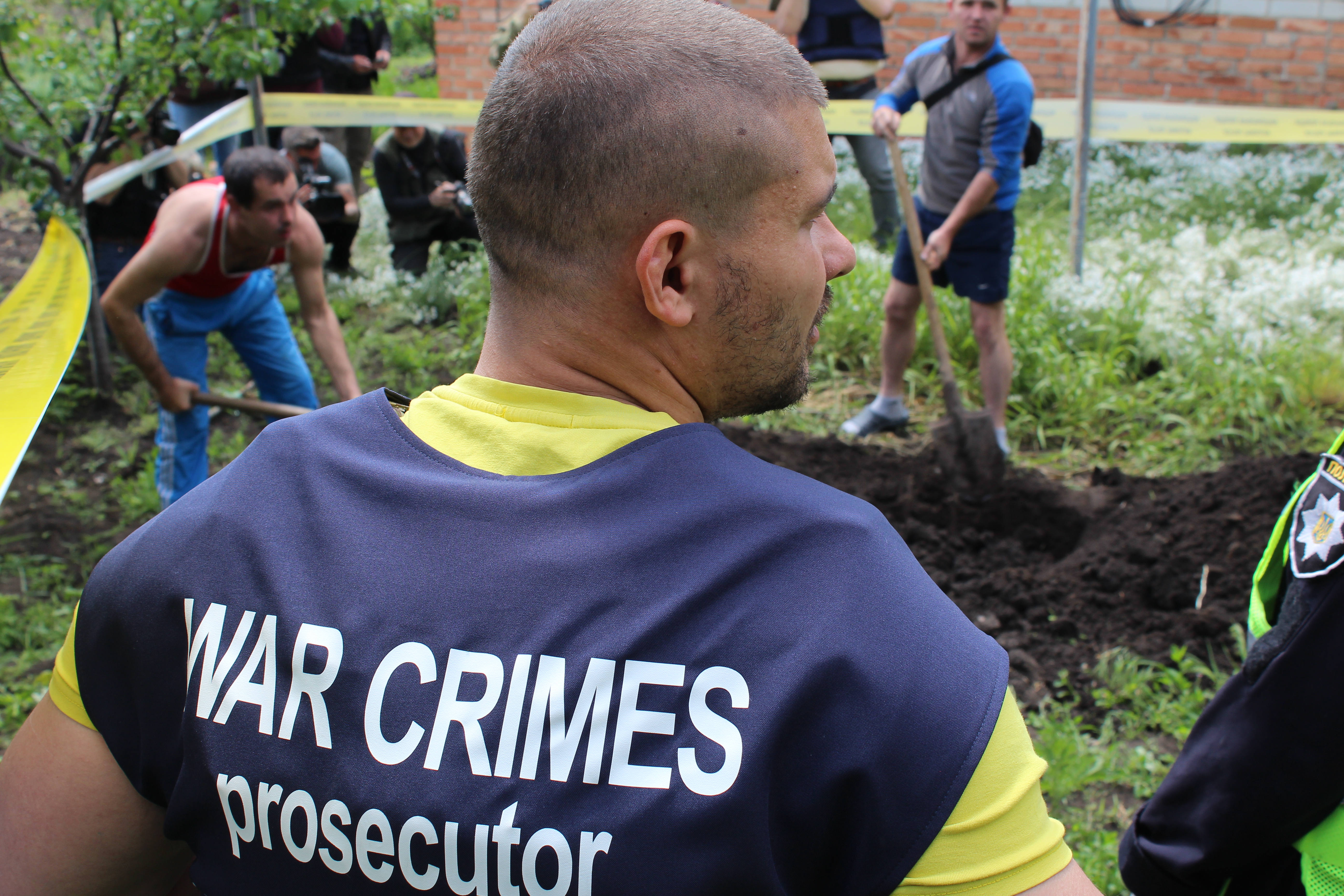 Oleksander Ilenkov, war crimes prosecutor for the Kharkiv region, watches the exhumation of a body in Mala Rohan, Ukraine, May 23, 2022.