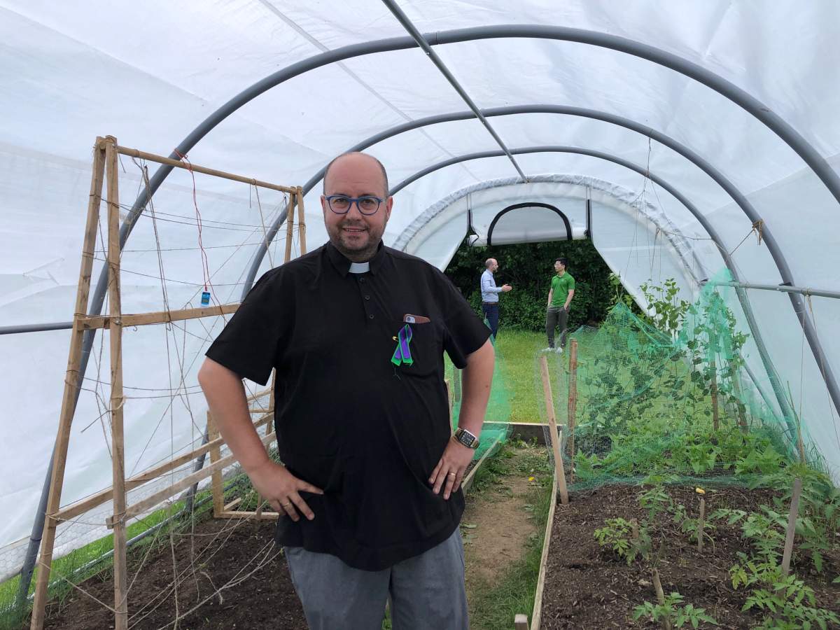 Canon Kevin George of St. Aidan’s Anglican Church inside one of their greenhouses.