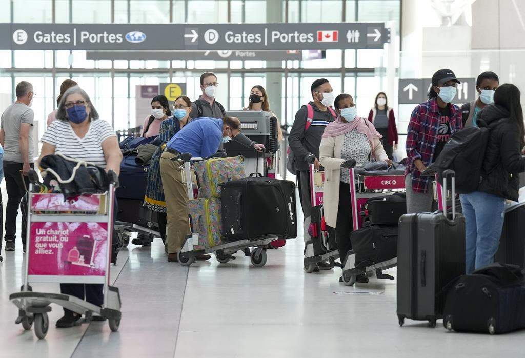 People wait in line to check in at Pearson International Airport in Toronto on Thursday, May 12, 2022.