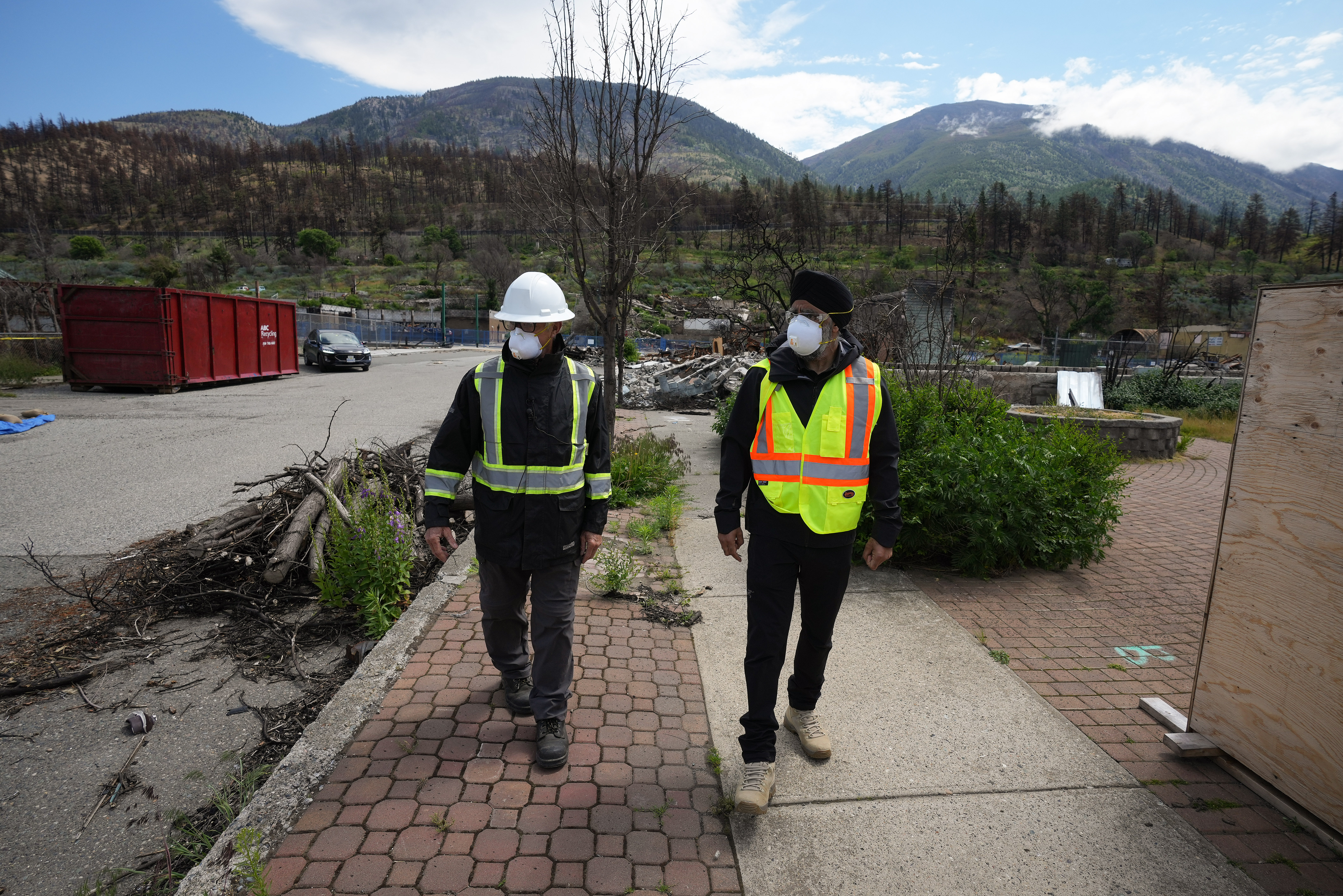 Harjit Sajjan, right, minister of International Development, views wildfire damage with Owen Collings, a resident who works as site support for the village, in Lytton, B.C., on Tuesday, June 14, 2022. The fire-ravaged community of Lytton, B.C., will get $77 million from the federal government to help it rebuild a fire-resistant and energy-efficient community. Two people were killed and much of the centre of the village was destroyed when wildfire ripped through the community almost a year ago.