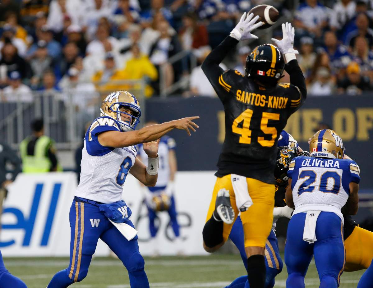 Winnipeg Blue Bombers quarterback Zach Collaros’ (8) throw gets knocked down by Hamilton Tiger-Cats’ Jovan Santos-Knox (45) during the first half of CFL action in Winnipeg, Friday, June 24, 2022. JOHN WOODS/THE CANADIAN PRESS