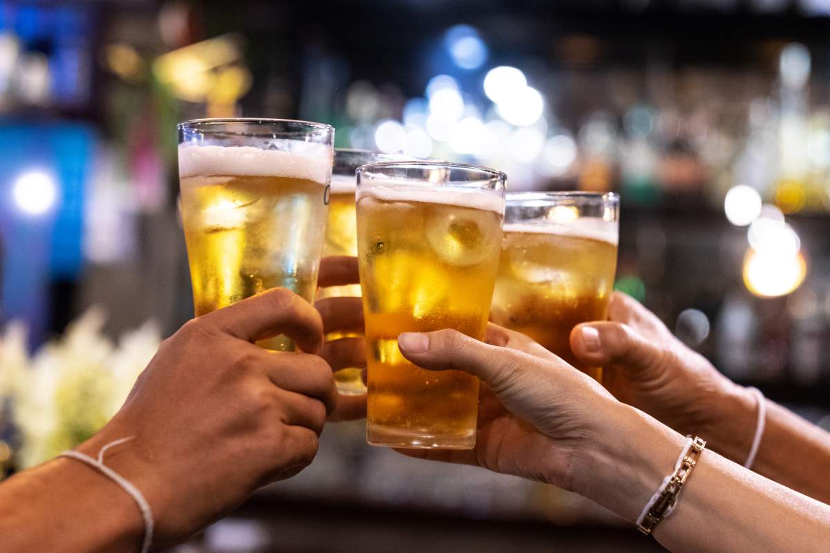 Group of friends drinking and toasting beers at a bar.