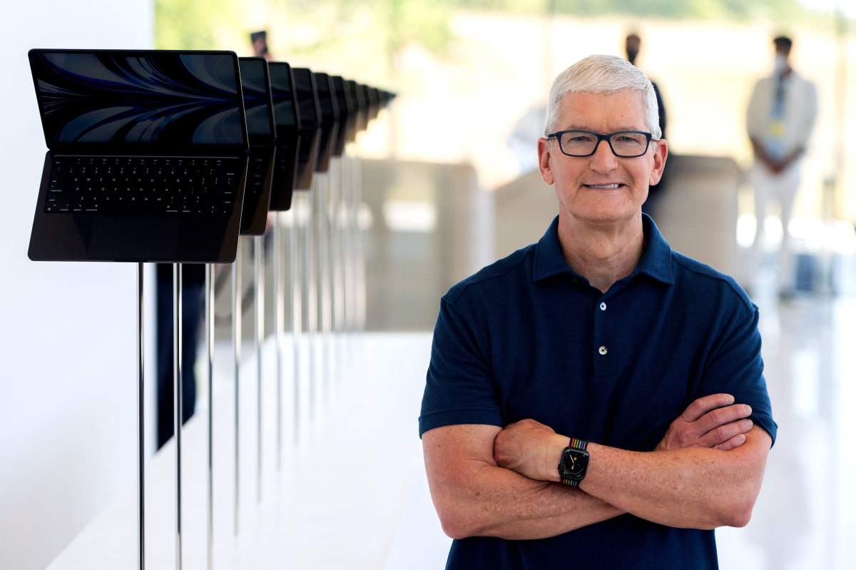 Apple CEO Tim Cook poses for a portrait next to a line of new MacBook Airs as he enters the Steve Jobs Theater during the Apple Worldwide Developers Conference