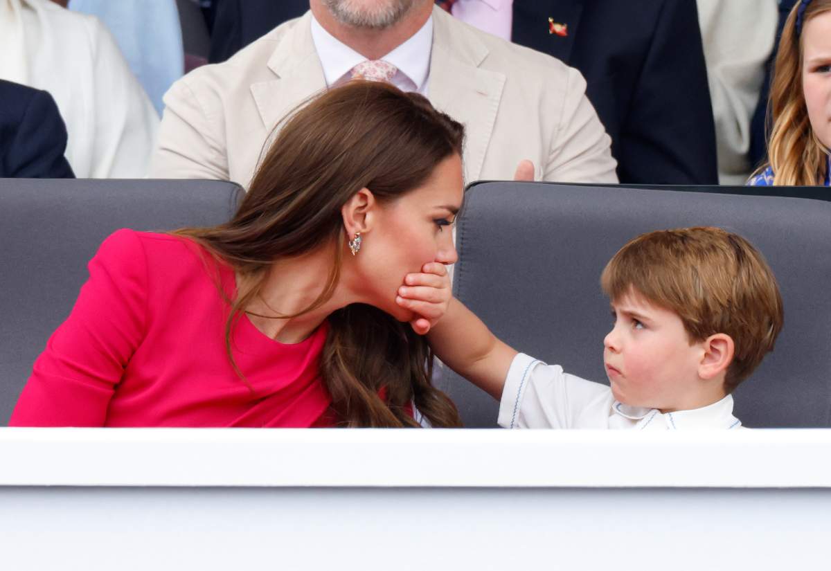 Prince Louis of Cambridge covers his mother Catherine, Duchess of Cambridge's mouth with his hand as they attend the Platinum Pageant on The Mall on June 5, 2022 in London, England.