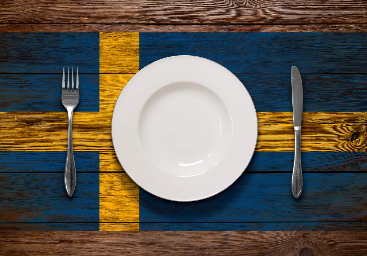A Swedish flag printed on a table with an empty place setting on top.