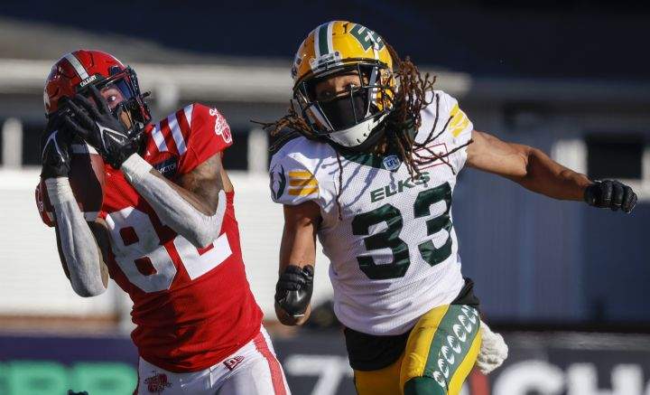 Edmonton Elks defensive back Jalen Collins, right, looks on as Calgary Stampeders receiver Malik Henry makes a catch during second half CFL football action in Calgary, Saturday, June 25, 2022.