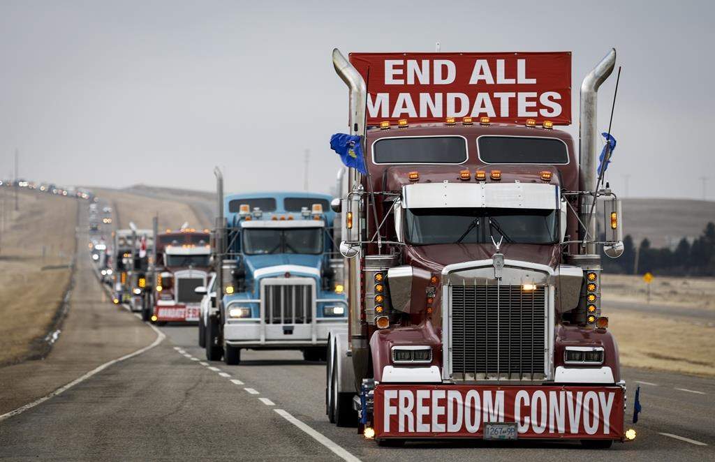 Anti-COVID-19 vaccine mandate demonstrators leave in a truck convoy after blocking the highway at the busy U.S. border crossing in Coutts, Alta., Tuesday, Feb. 15, 2022.