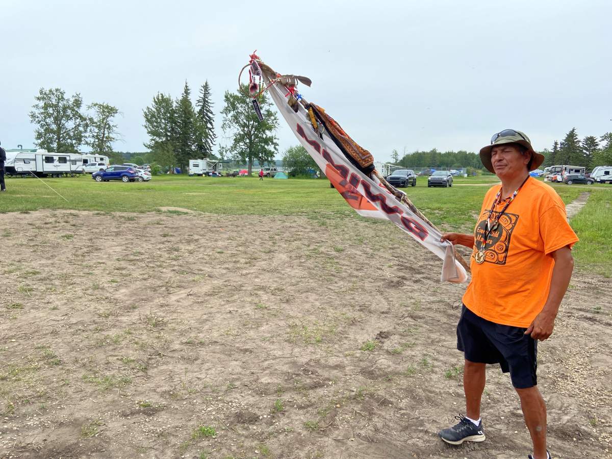 Adam McDonald holds an MMIW flag while standing on Alexis Nakota Sioux Nation grounds, Sunday, July 24, 2022.
