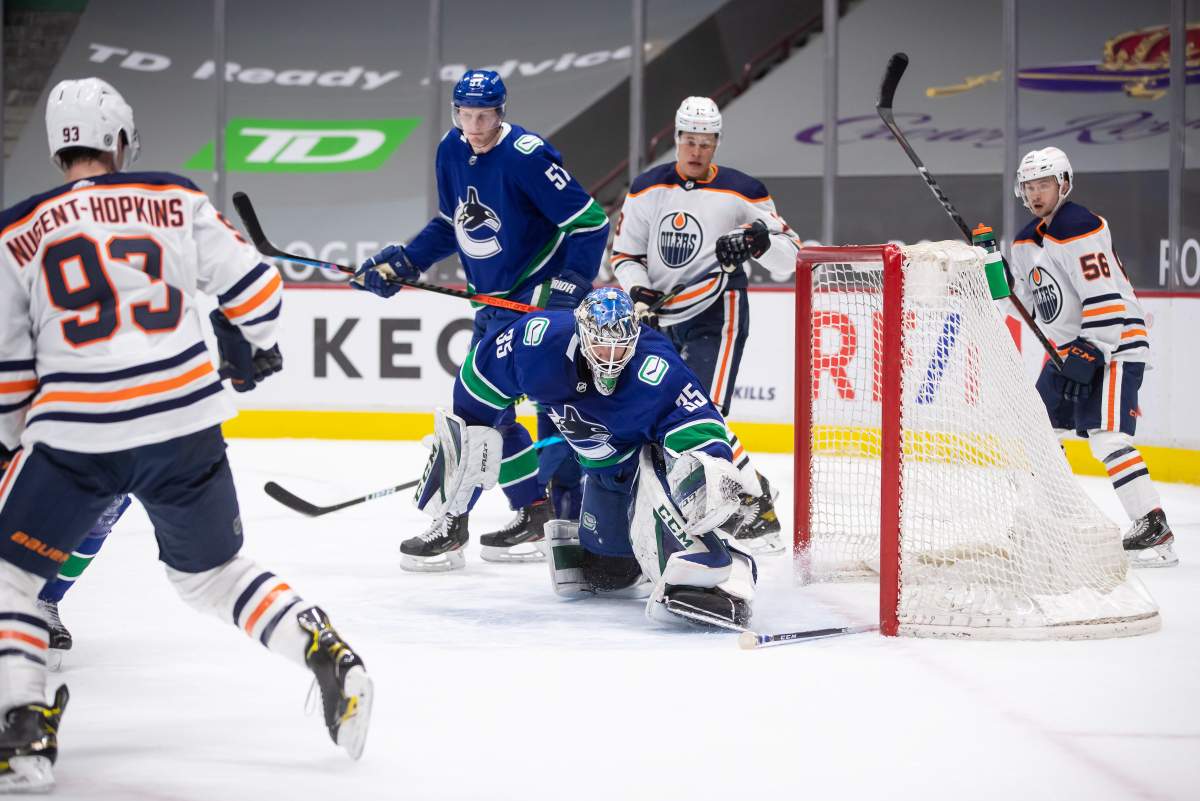 Vancouver Canucks goalie Thatcher Demko (35) makes a save as Edmonton Oilers’ Ryan Nugent-Hopkins (93), Jesse Puljujarvi (13), of Sweden, Kailer Yamamoto (56) and Vancouver’s Tyler Myers (57) watch during the third period of an NHL hockey game in Vancouver, on Saturday, March 13, 2021.