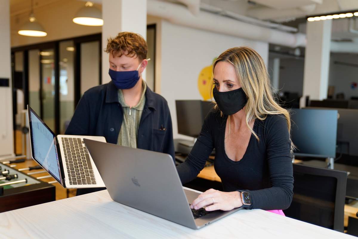 Kelly Soderlund, right, works with a colleague at the TripActions office in San Francisco, Friday, Aug. 27, 2021. Switching to a hybrid work model is ideal for people like Soderlund, a mother of two young children who works in offices in San Francisco and Palo Alto, California, for TripActions, which has about 1,200 employees worldwide. (AP Photo/Eric Risberg).
