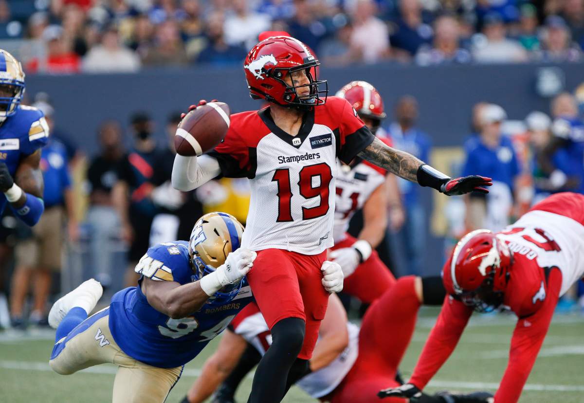 Winnipeg Blue Bombers’ Jackson Jeffcoat (94) gets a hold of Calgary Stampeders quarterback Bo Levi Mitchell (19) as he throws during the first half of CFL action in Winnipeg, Friday, July 15, 2022.