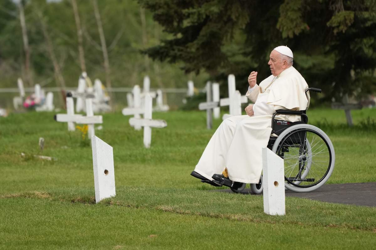 Pope Francis prays at a gravesite at the Ermineskin Cree Nation Cemetery in Maskwacis, Alta., during his papal visit across Canada on Monday, July 25, 2022.