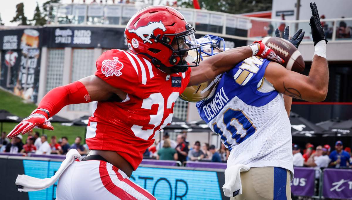 Winnipeg Blue Bombers receiver Nic Demski, right, tries to catch a pass as Calgary Stampeders defensive back Titus Wall grabs for him during first half CFL football action in Calgary, Saturday, July 30, 2022.