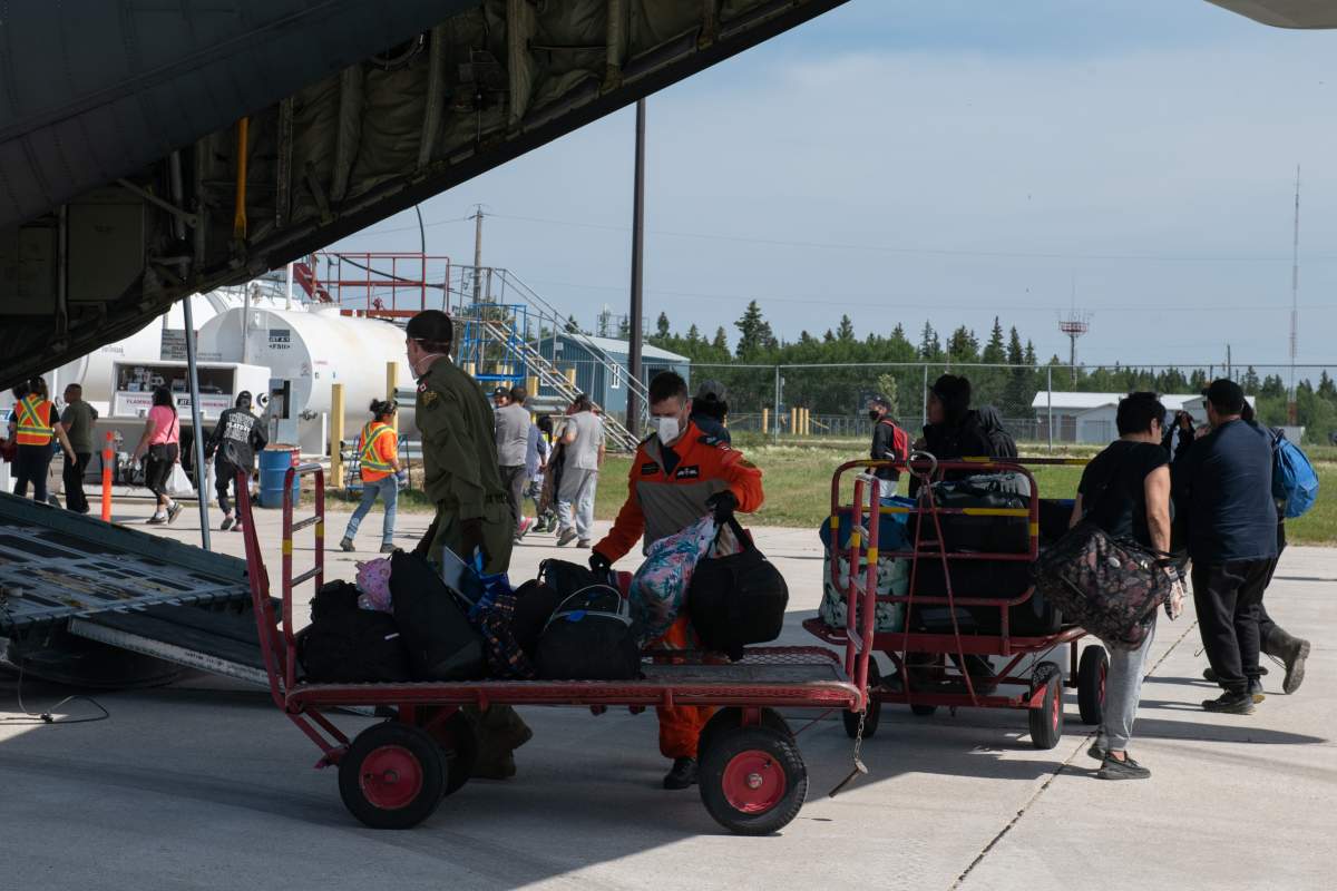 : Members of 435 Transport and Rescue Squadron unload evacuees’ luggage at The Pas airport on July 16, 2022.