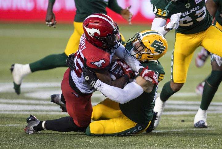 Calgary Stampeders’ Ka’Deem Carey (35) is tackled by Edmonton Elks’ Scott Hutter (20) during second half CFL action in Edmonton, Alta., on Thursday July 7, 2022.