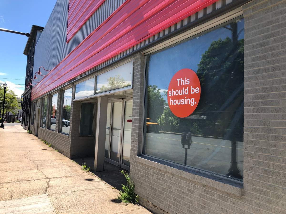 A This Should be Housing sticker displayed in a vacant downtown Bridgewater building