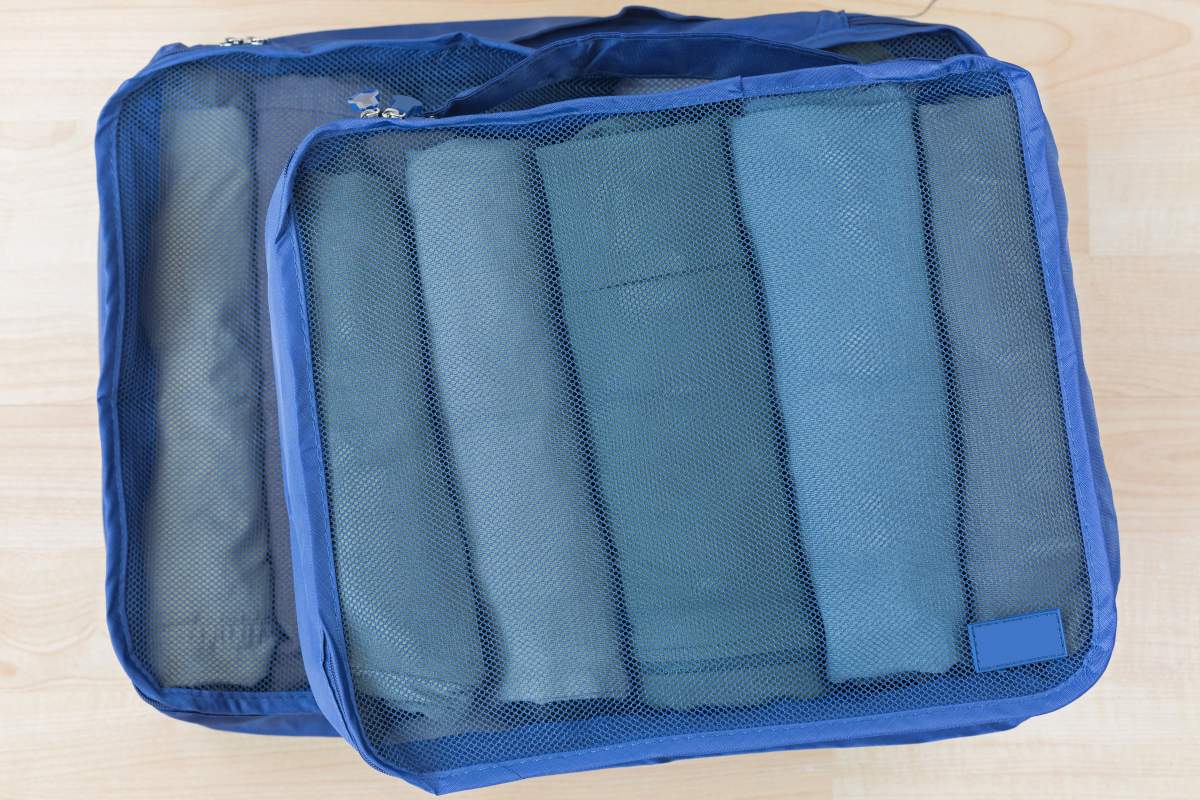Rolled clothes appear in blue, mesh packing cubes