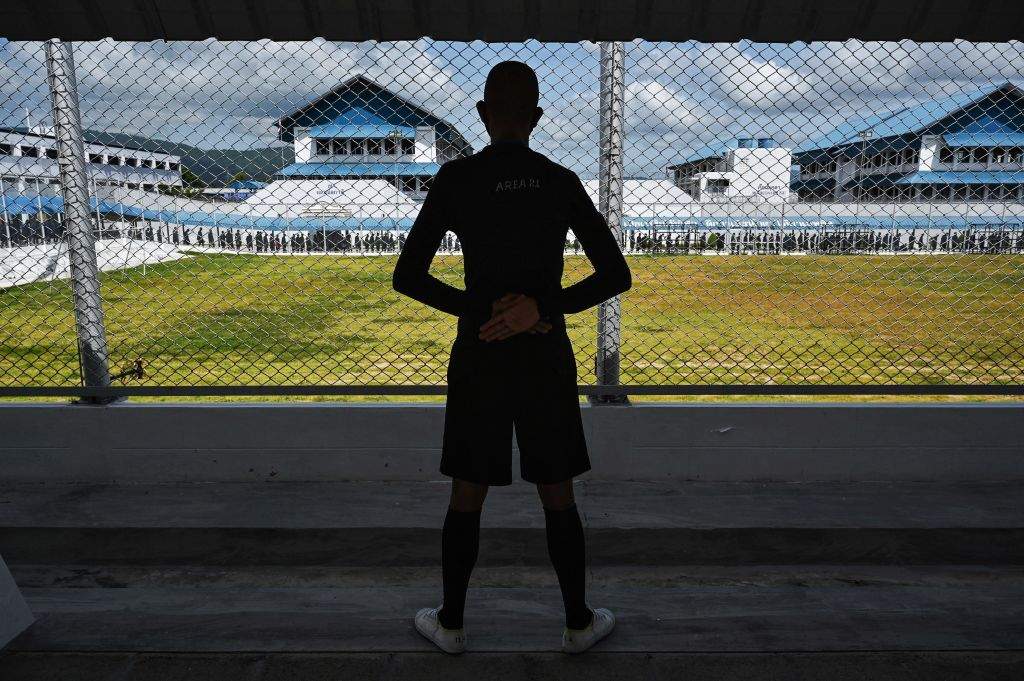 An inmate, tasked with different duties as a reward for good behaviour, keeps watch as other inmates line up to receive doses of the Sinopharm Covid-19 coronavirus vaccine at Chonburi Central Prison on June 25, 2021.