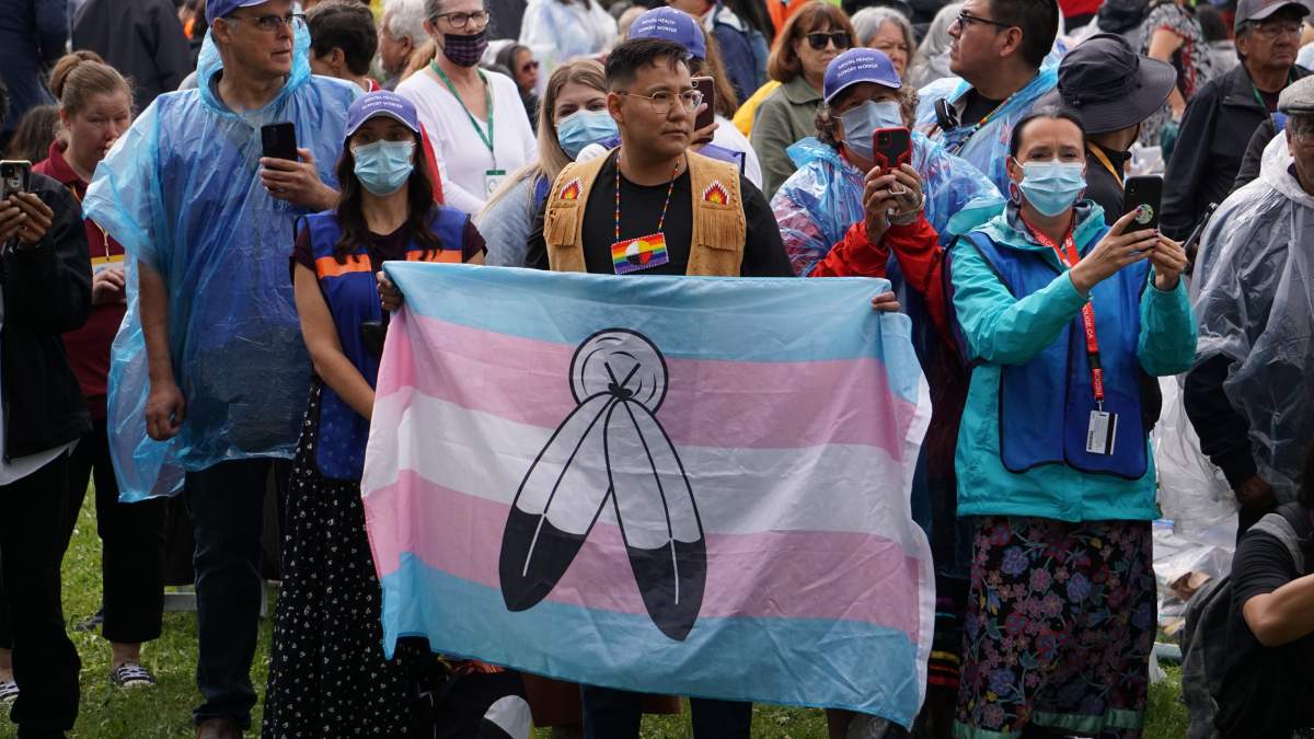 Samson Cree Nation's Jack Saddleback holds up a trans and two-spirit pride flag during the grand entry at the Bear Park arbour in Maskwacis, Alta. on Mon. July 25, 2022. Pope Francis made his first apology for residential schools in Maskwacis, his first official event of the six-day papal tour.