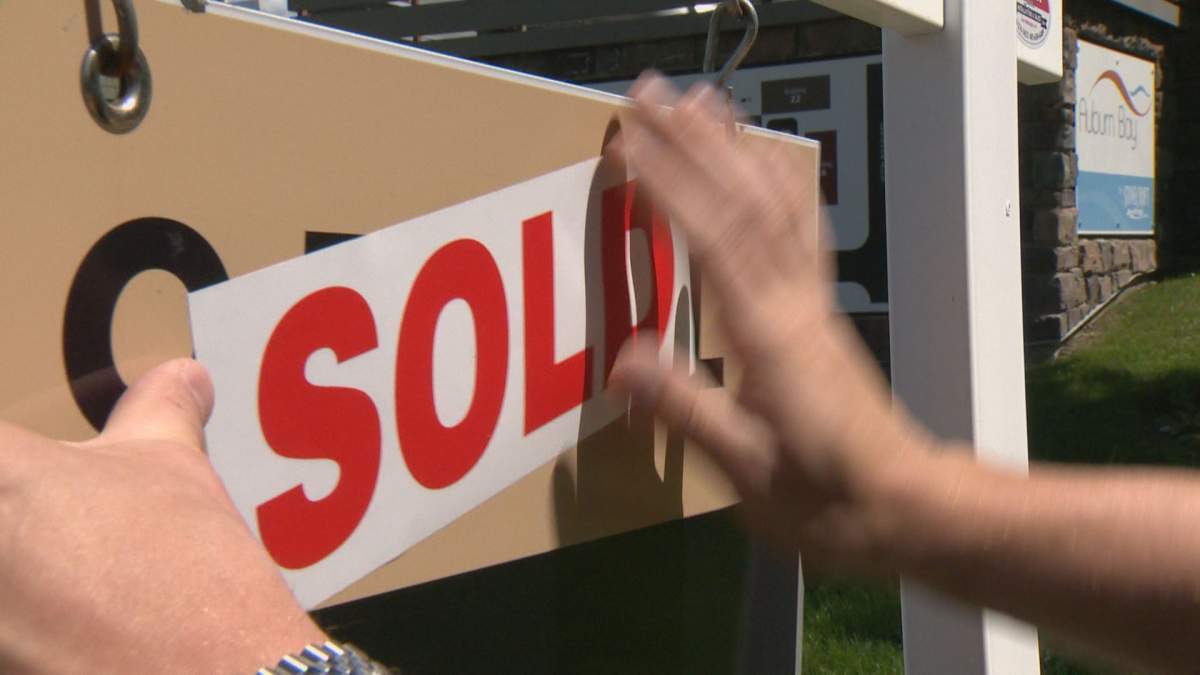 A "sold" sticker is added to a real estate sign in Calgary, pictured on July 19, 2022.